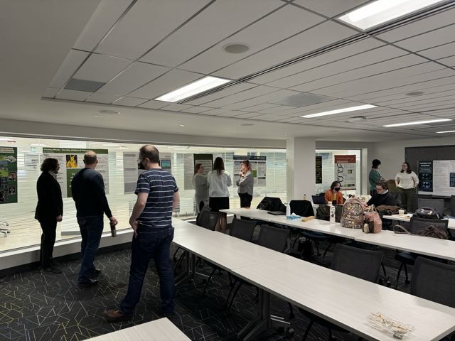 Poster session image with people viewing posters in the conference room